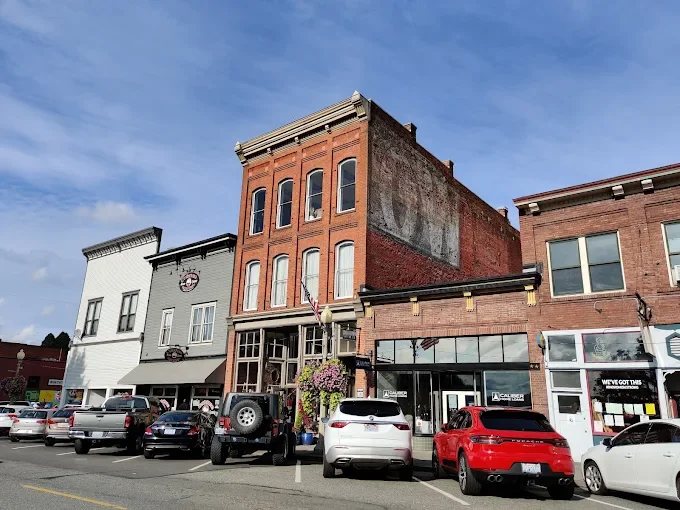 Luxury black chauffeur sedan parked in historic downtown Snohomish near antique storefronts